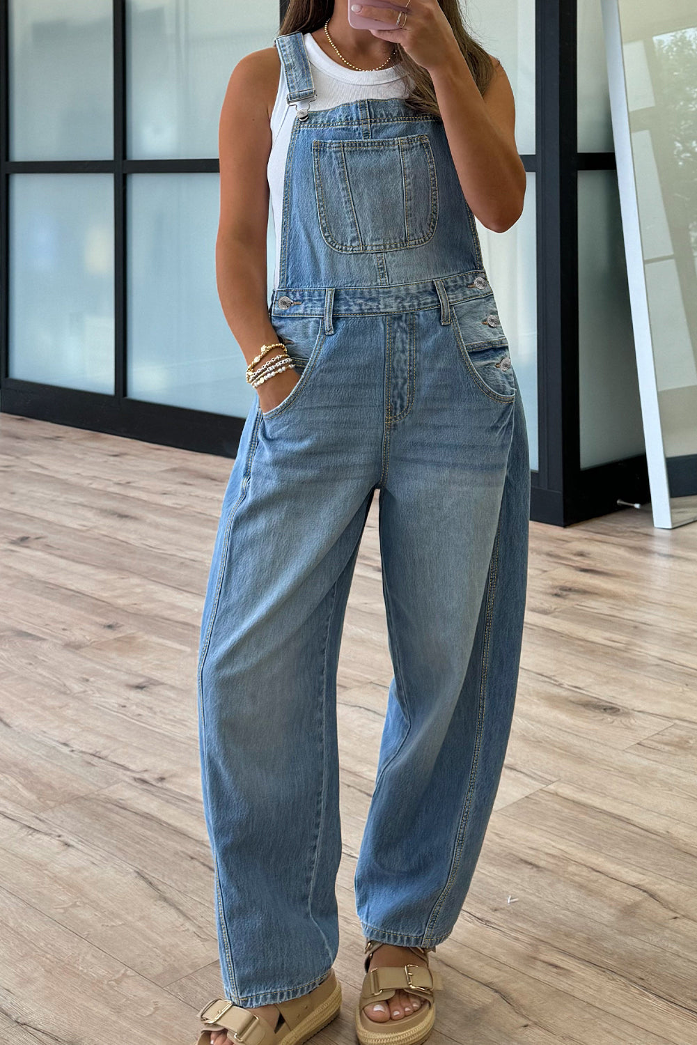 Person wearing denim overalls standing on a wooden floor.