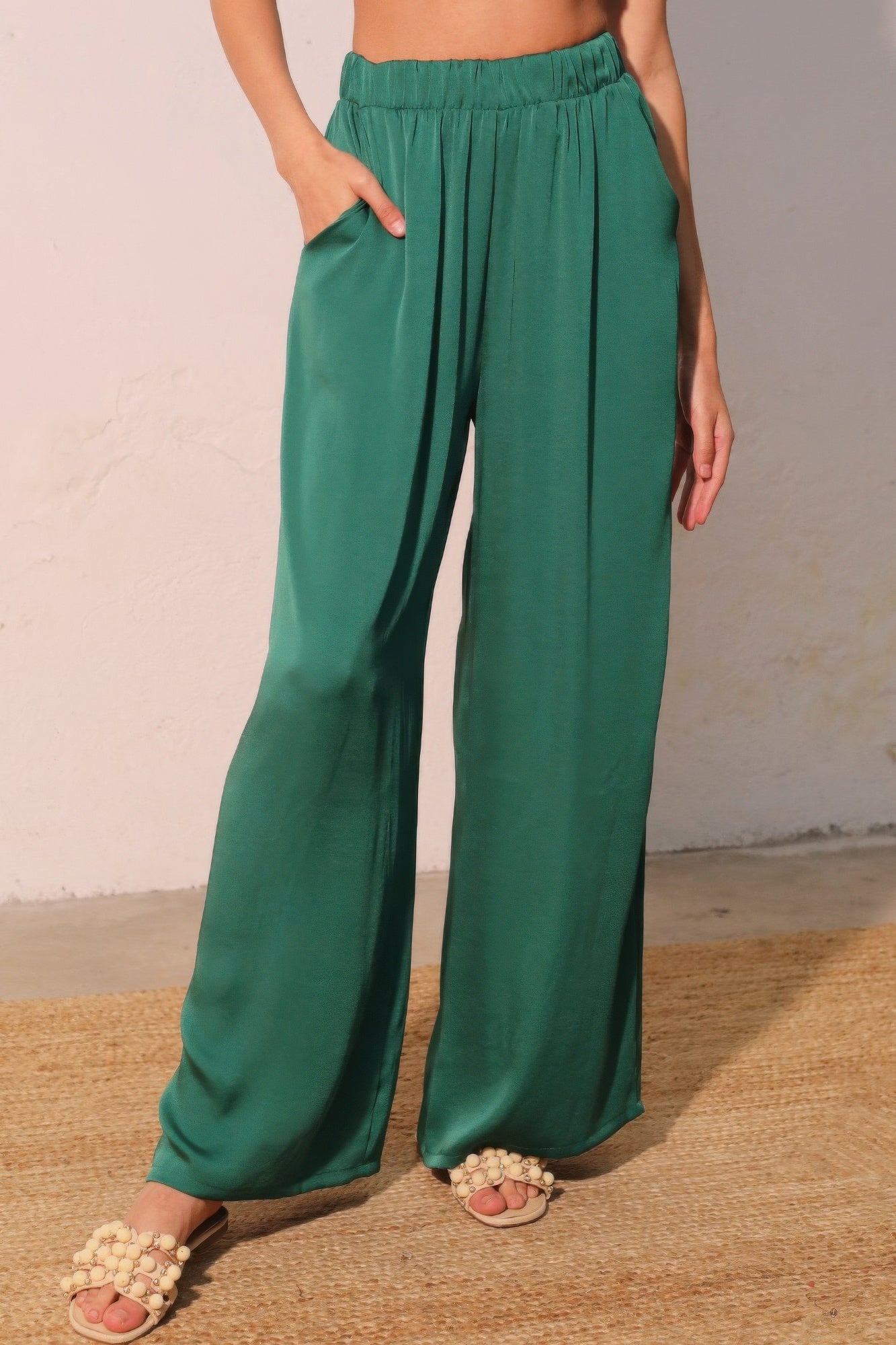 Green wide-leg pants worn by a person on a neutral background