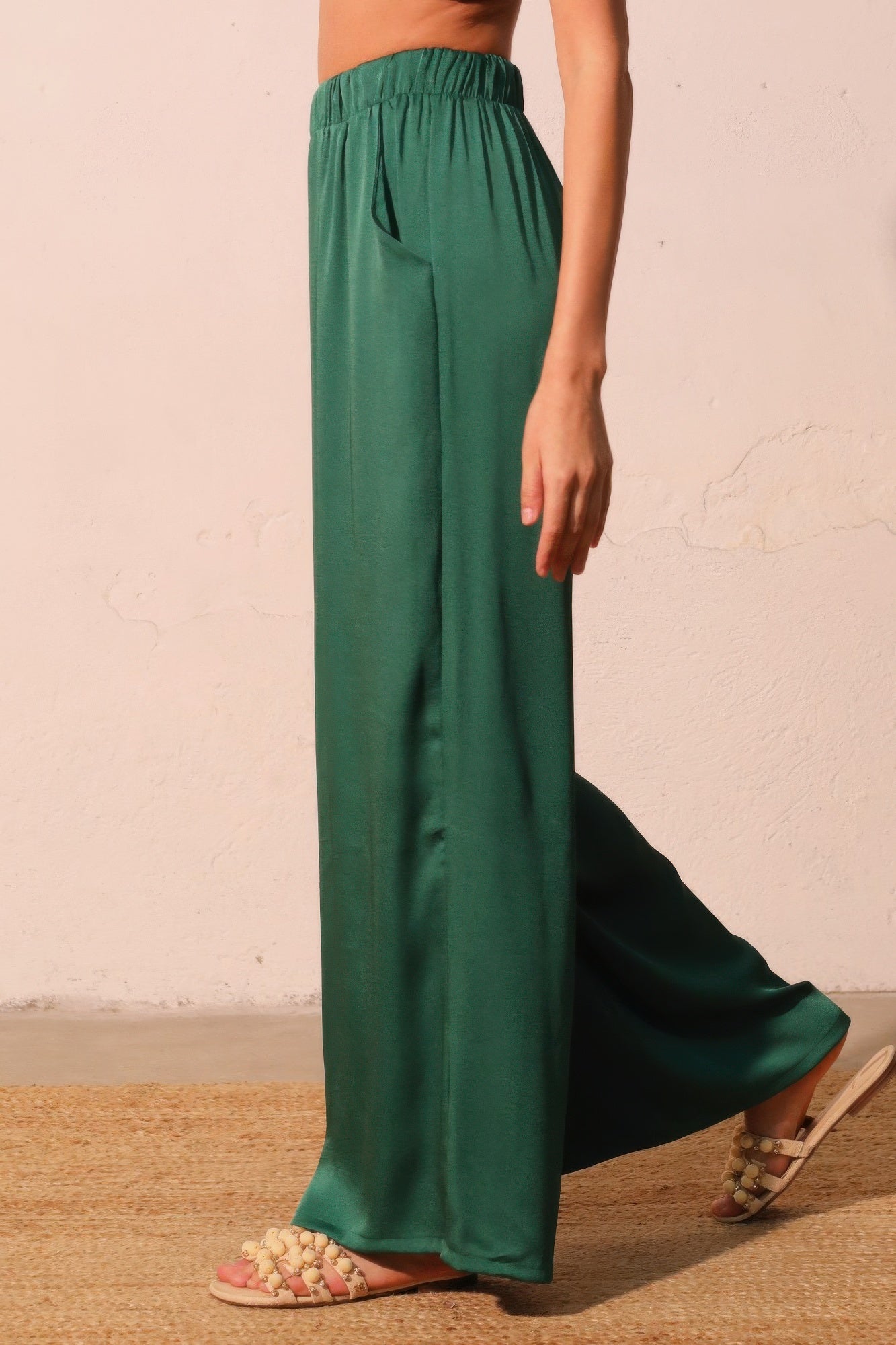 Green wide-leg pants worn by a person on a neutral background side view