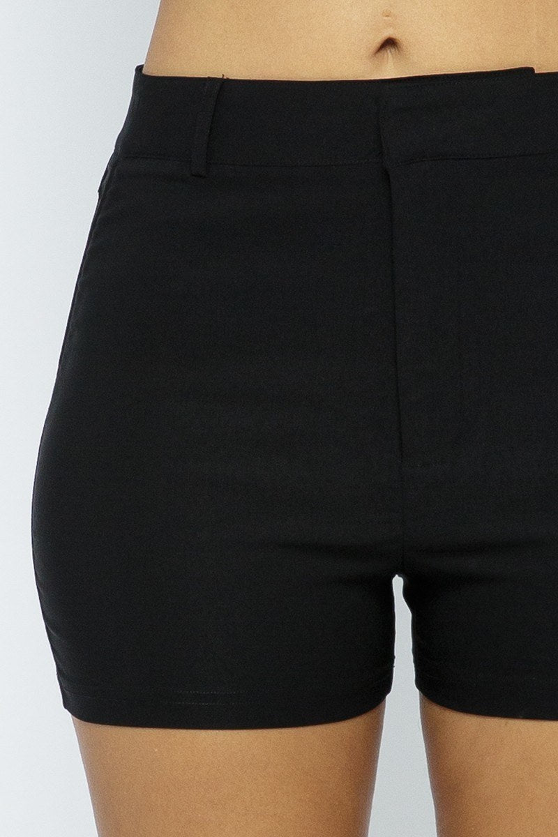 Black shorts worn by a person on a plain background close up