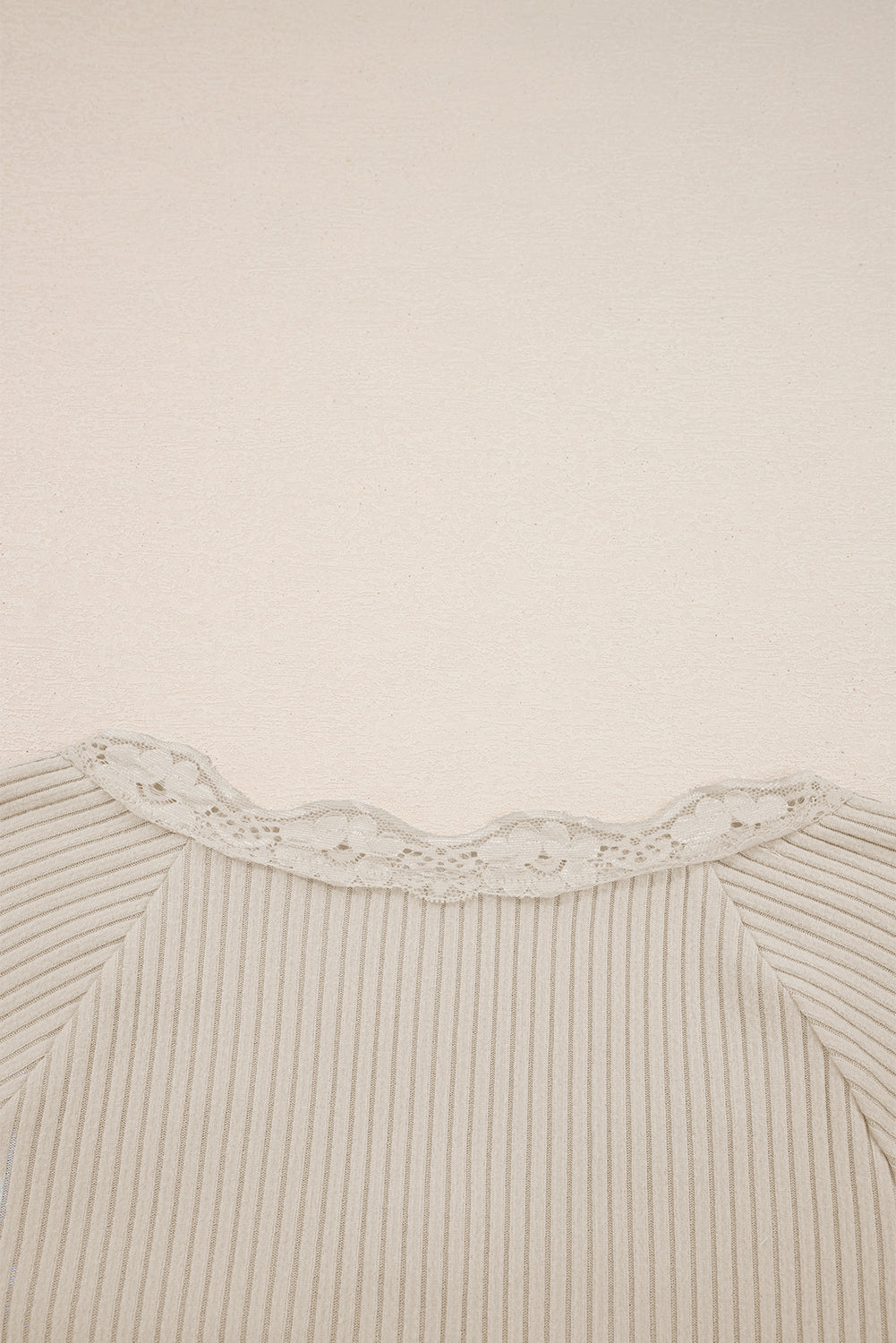 Close-up of a ribbed sweater with lace trim on a beige background