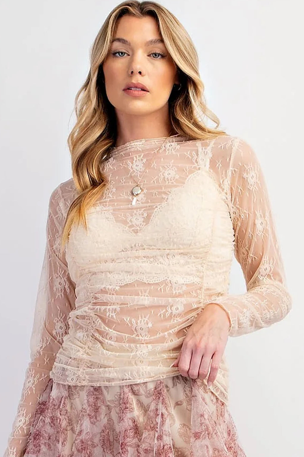 Woman wearing a beige lace dress with long sleeves on a white background front view