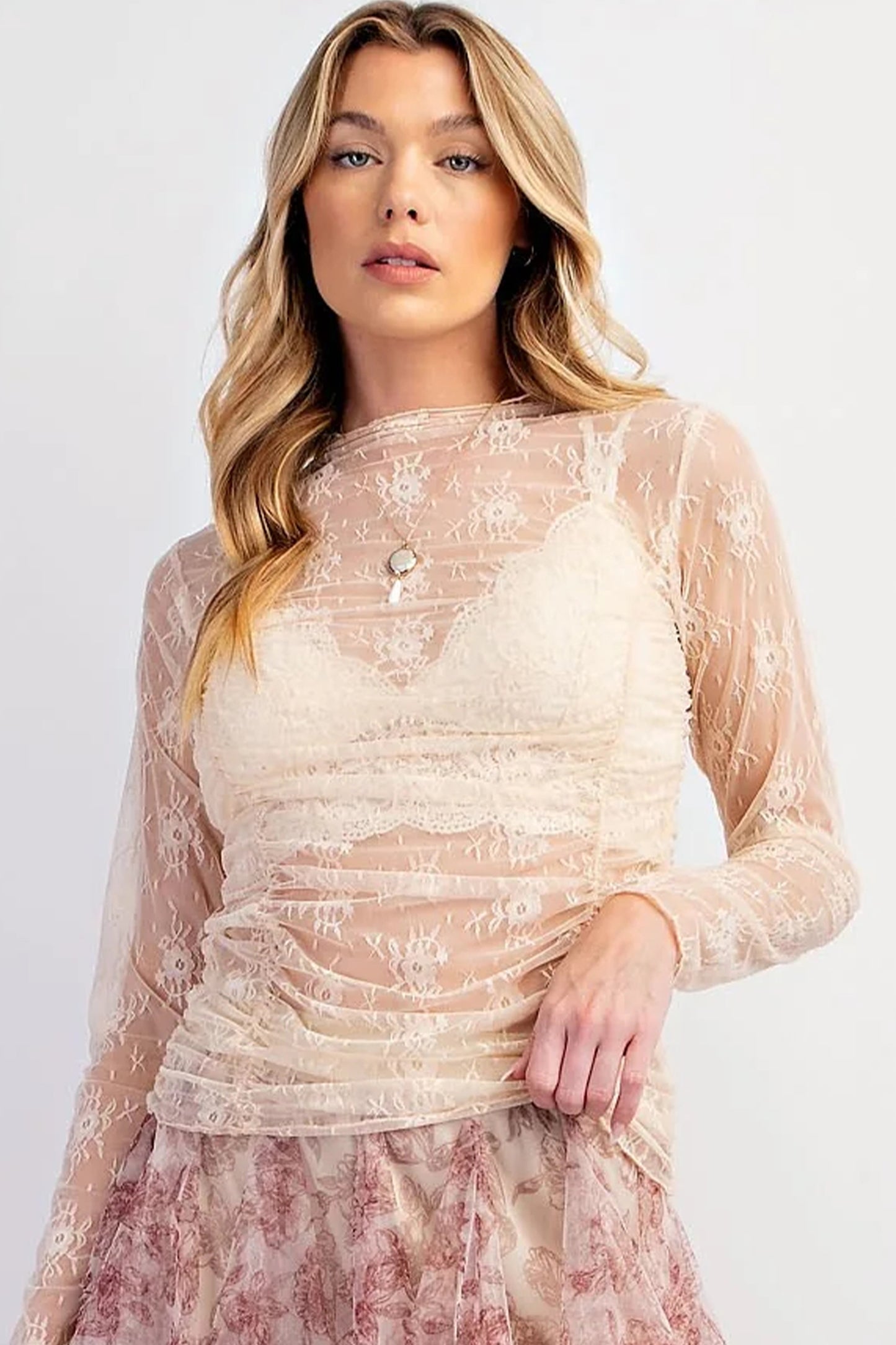 Woman wearing a beige lace dress with long sleeves on a white background front view