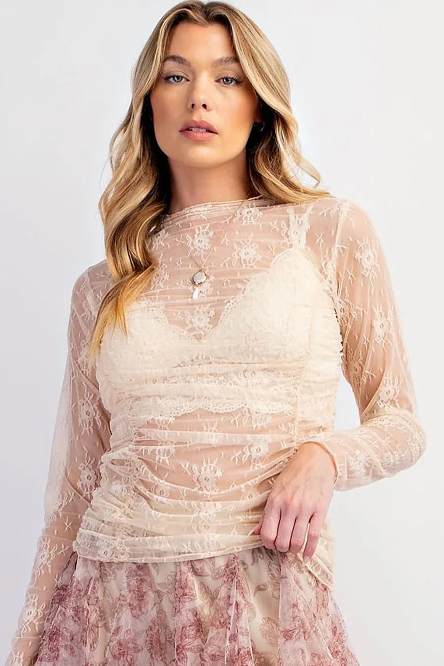 Woman wearing a beige lace dress with long sleeves on a white background front view