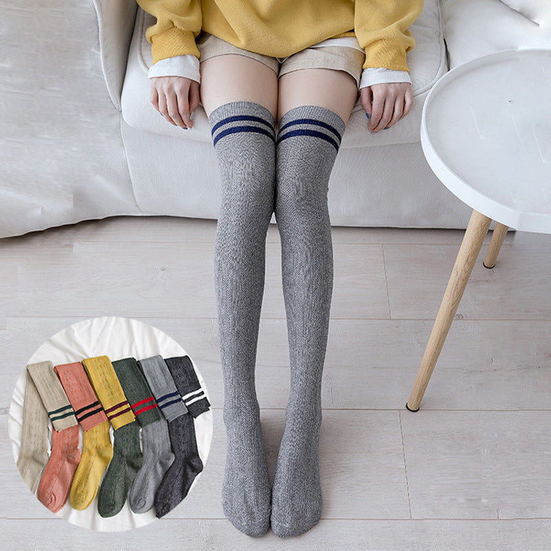 Person wearing gray knee-high socks with striped cuffs, sitting on a couch.