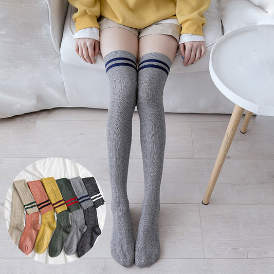 Person wearing gray knee-high socks with striped cuffs, sitting on a couch.