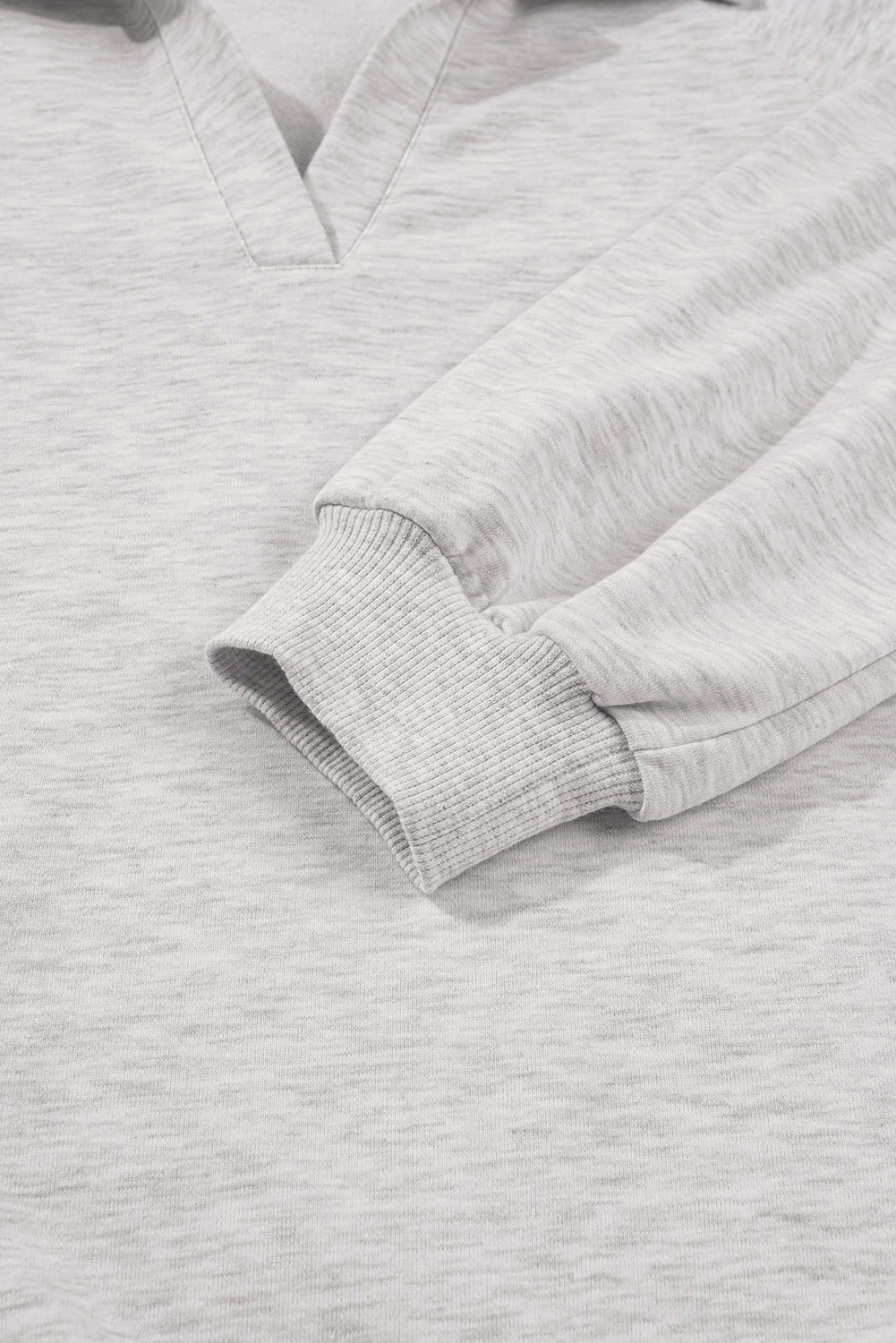 Close-up of a gray sweatshirt with a focus on the sleeve and collar.