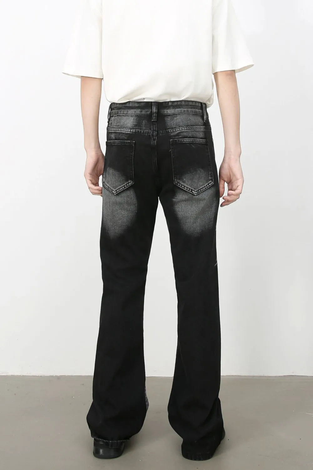 Male Model wearing a pair of black acid wash Bootcut Jeans back view