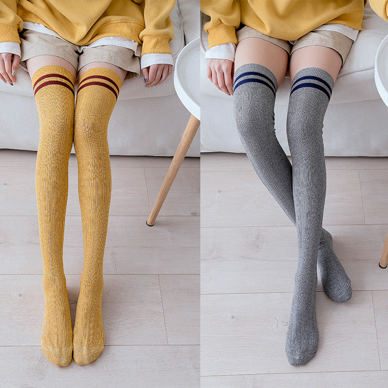Two sets of knee-high socks, one yellow and one gray, worn by a person sitting on a couch.