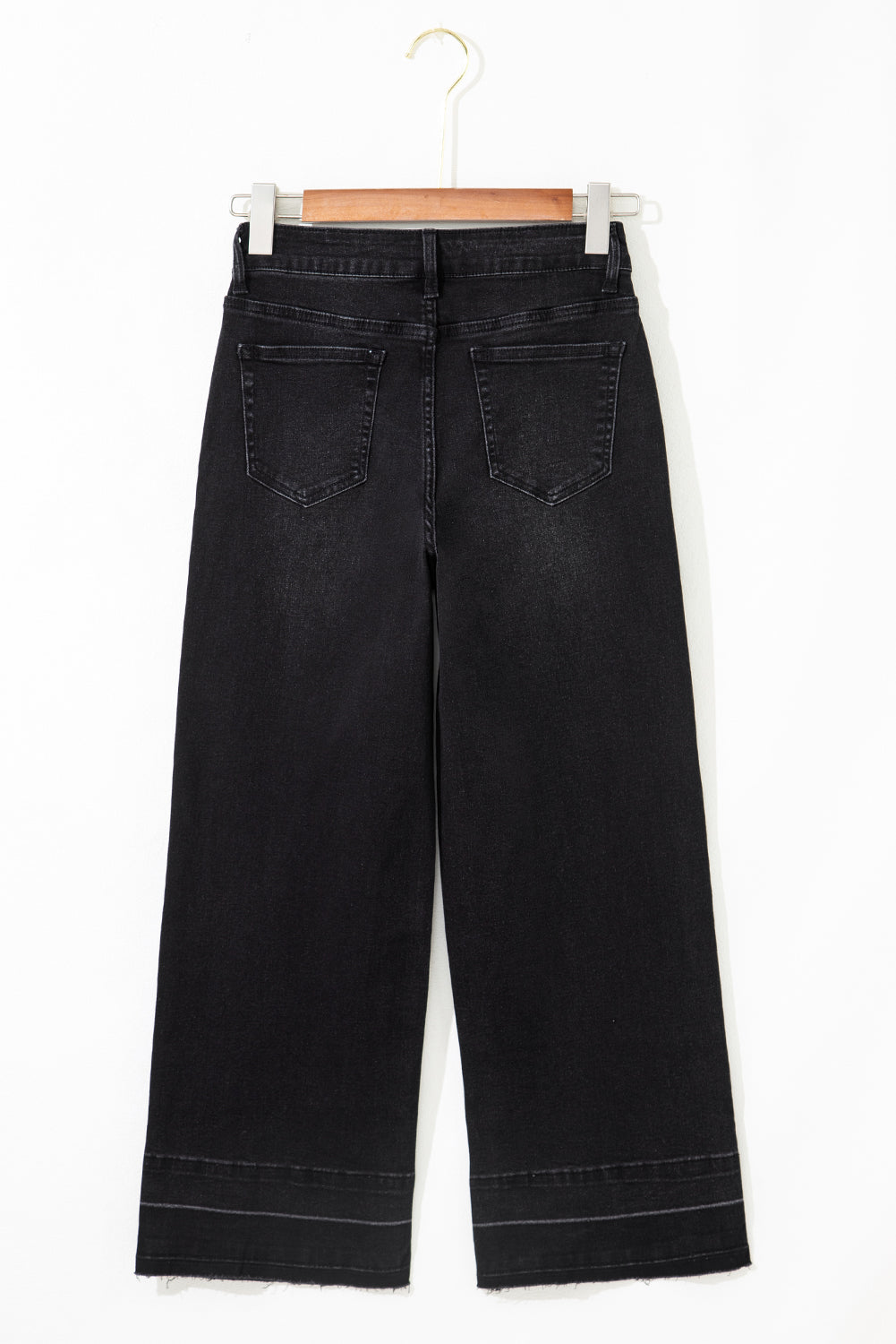 Black wide-leg jeans on a hanger against a white background