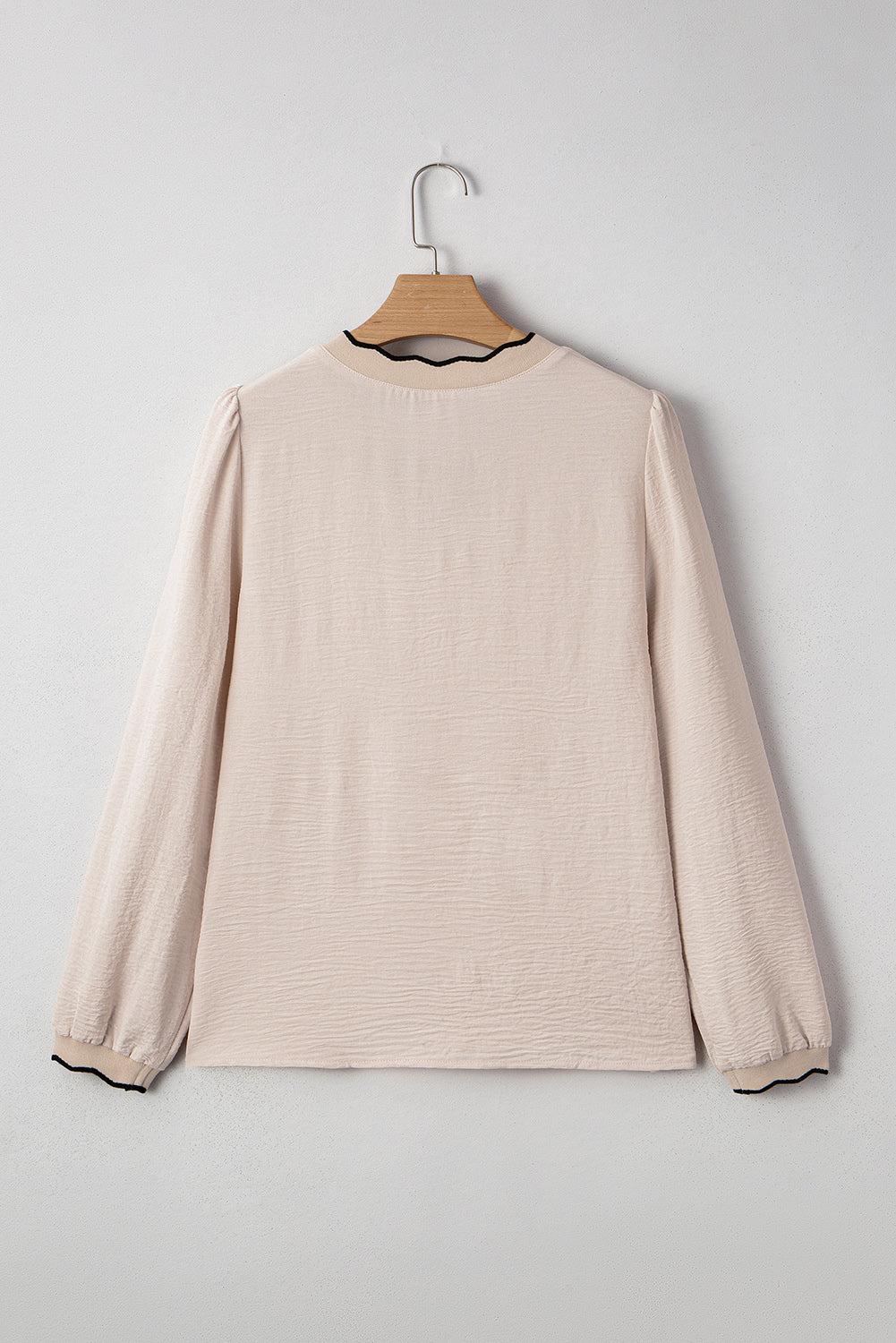 Beige long-sleeve shirt on a hanger against a light gray background