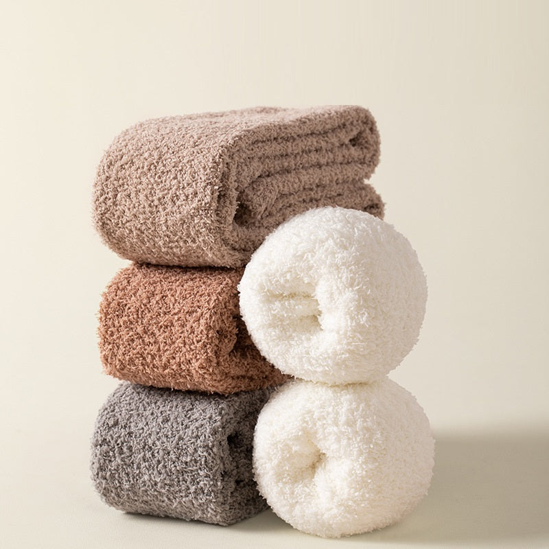 Stack of folded textured socks in brown, beige, and gray on a light background