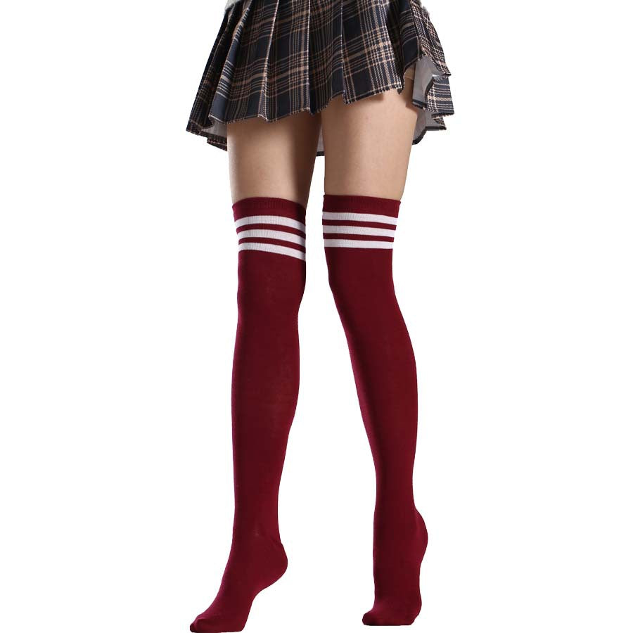 Red knee-high socks with white stripes worn with a plaid skirt on a white background