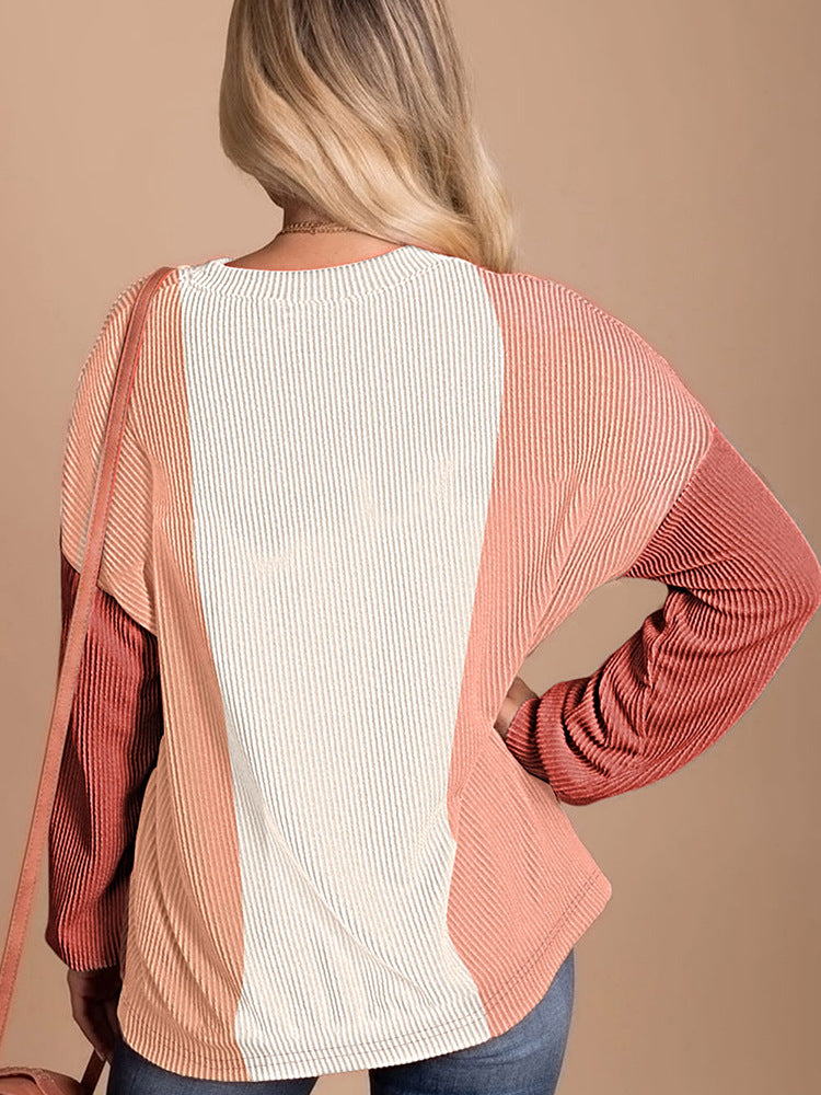 Person wearing a two-tone ribbed sweater with a plain background