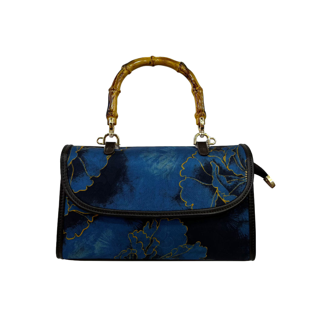Blue handbag with floral design and bamboo handle on a white background