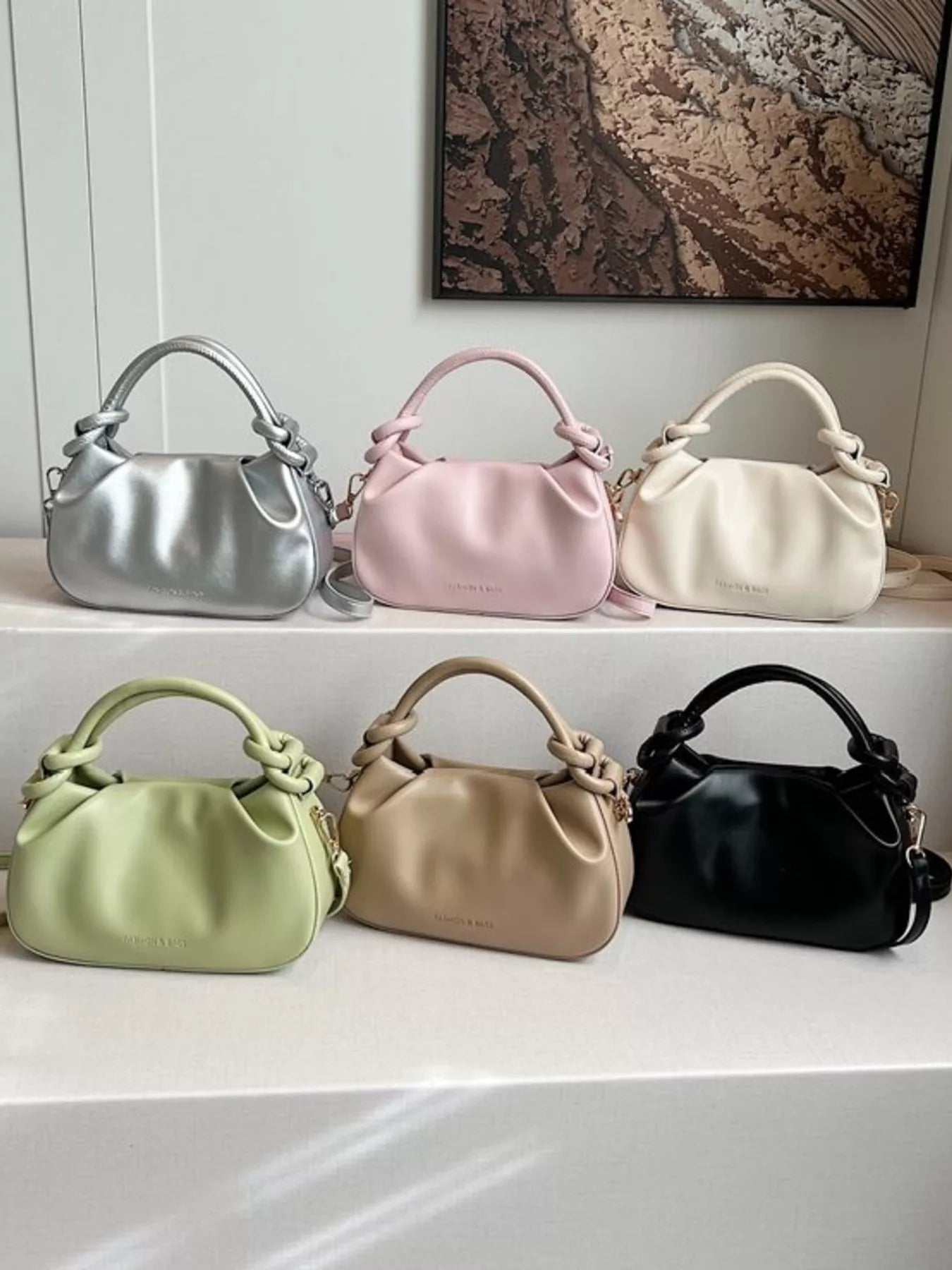 Six handbags in different colors displayed on a shelf.