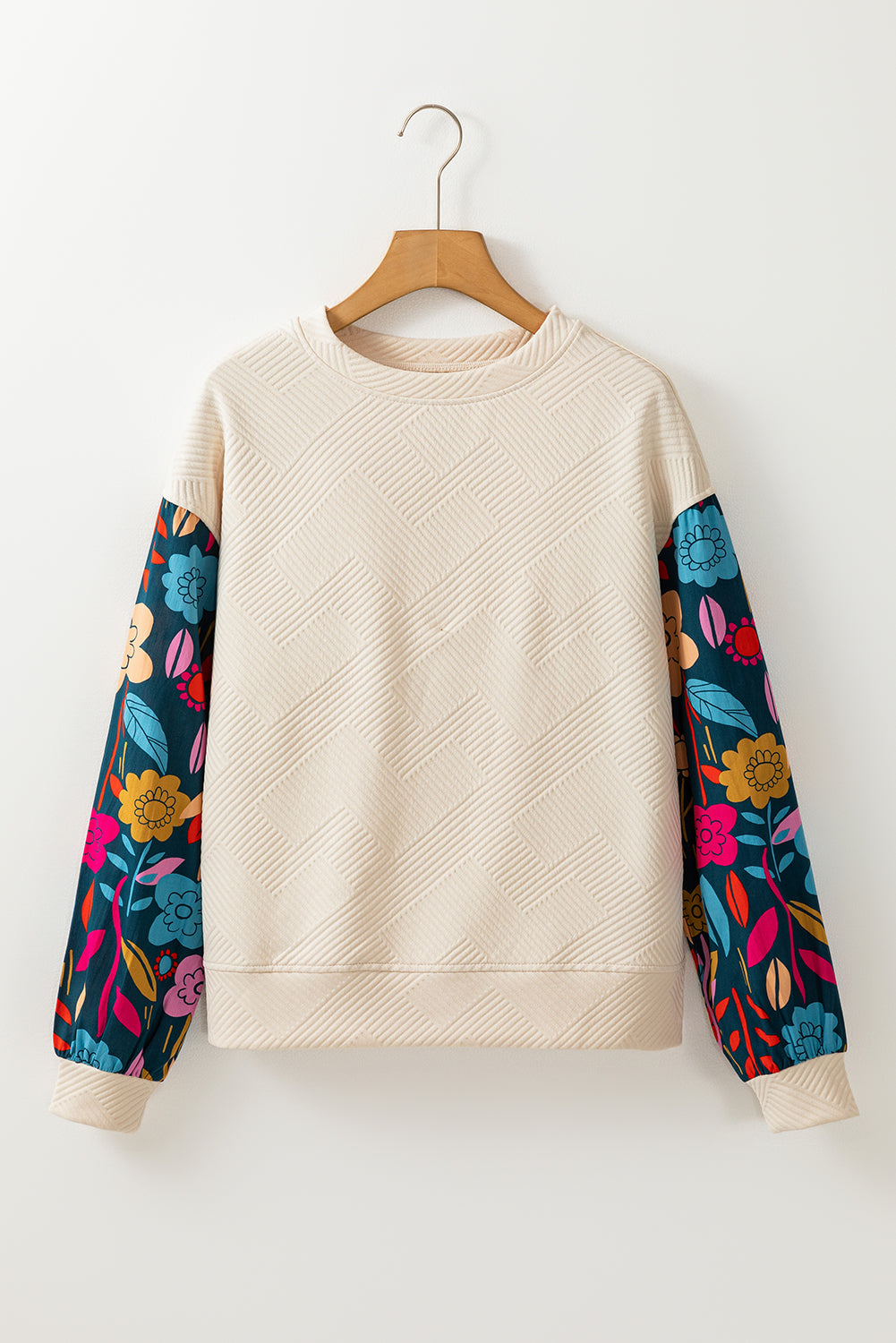 Beige sweatshirt with colorful floral sleeves on a wooden hanger against a white background