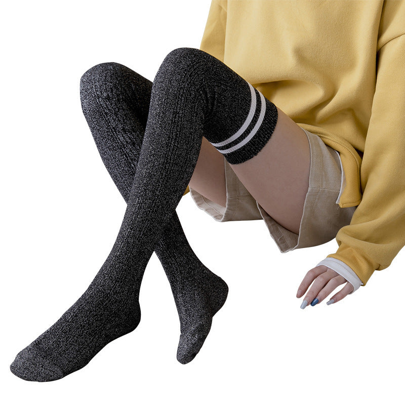 Person wearing black knee-high socks with white stripes on a white background
