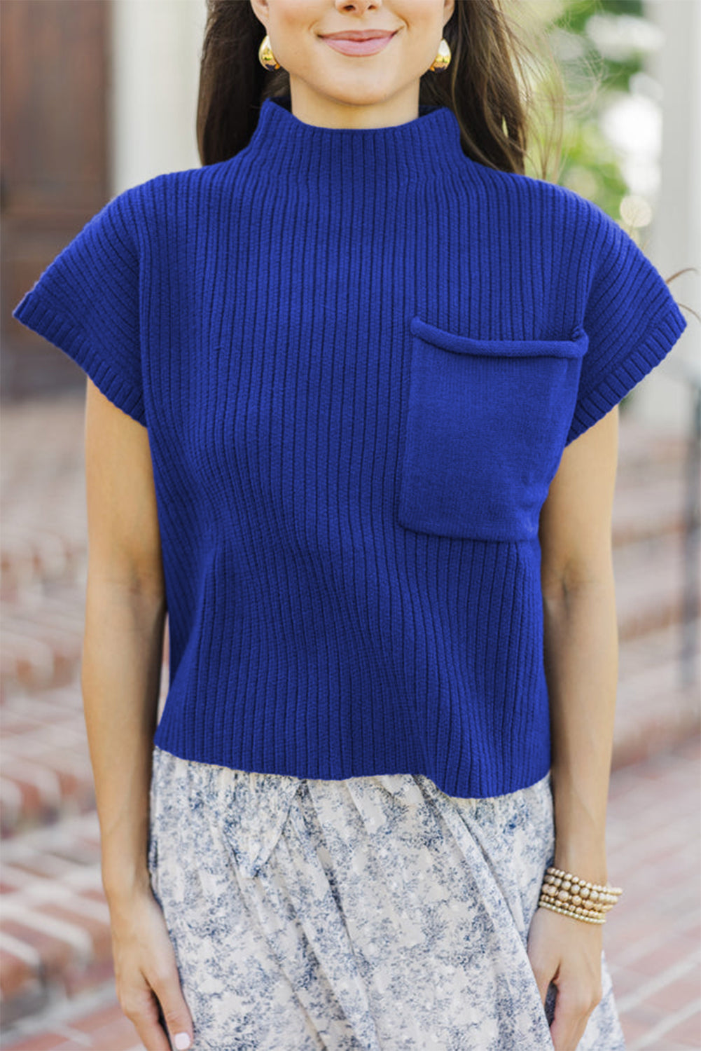 Woman wearing a blue ribbed sweater with a pocket outdoors.