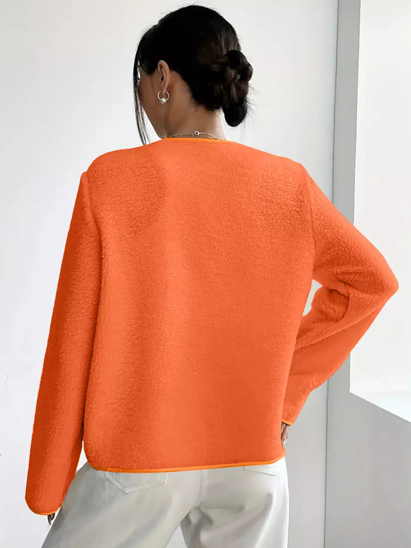 Person wearing an orange sweater against a white background