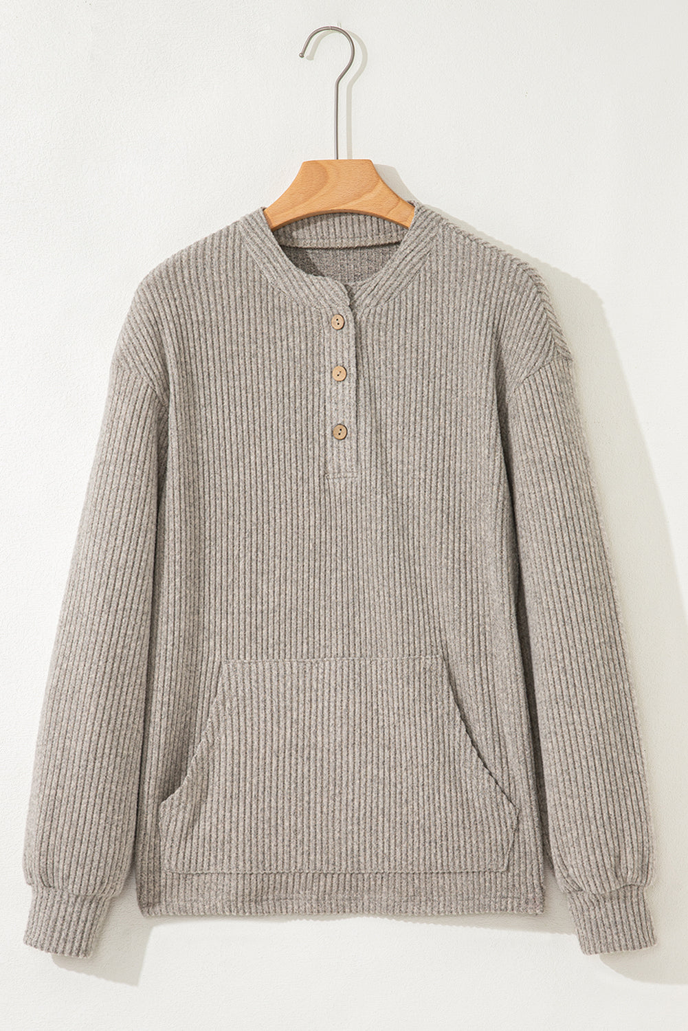 Gray ribbed sweater on a wooden hanger against a white background