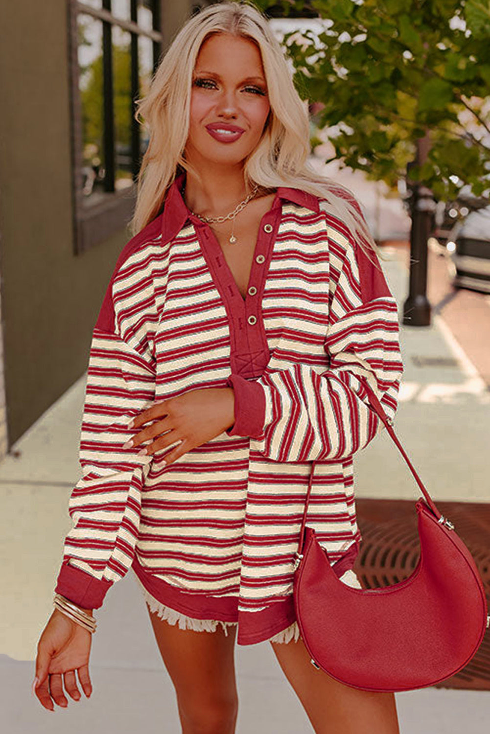 Woman wearing a red and white striped outfit with a red handbag outdoors.