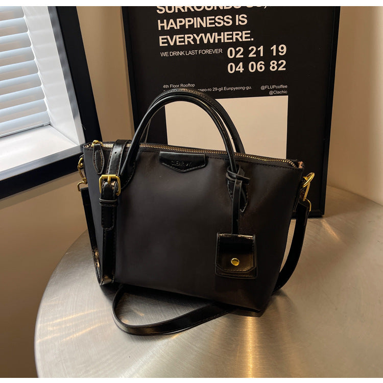 Black handbag on a reflective surface with a blurred background