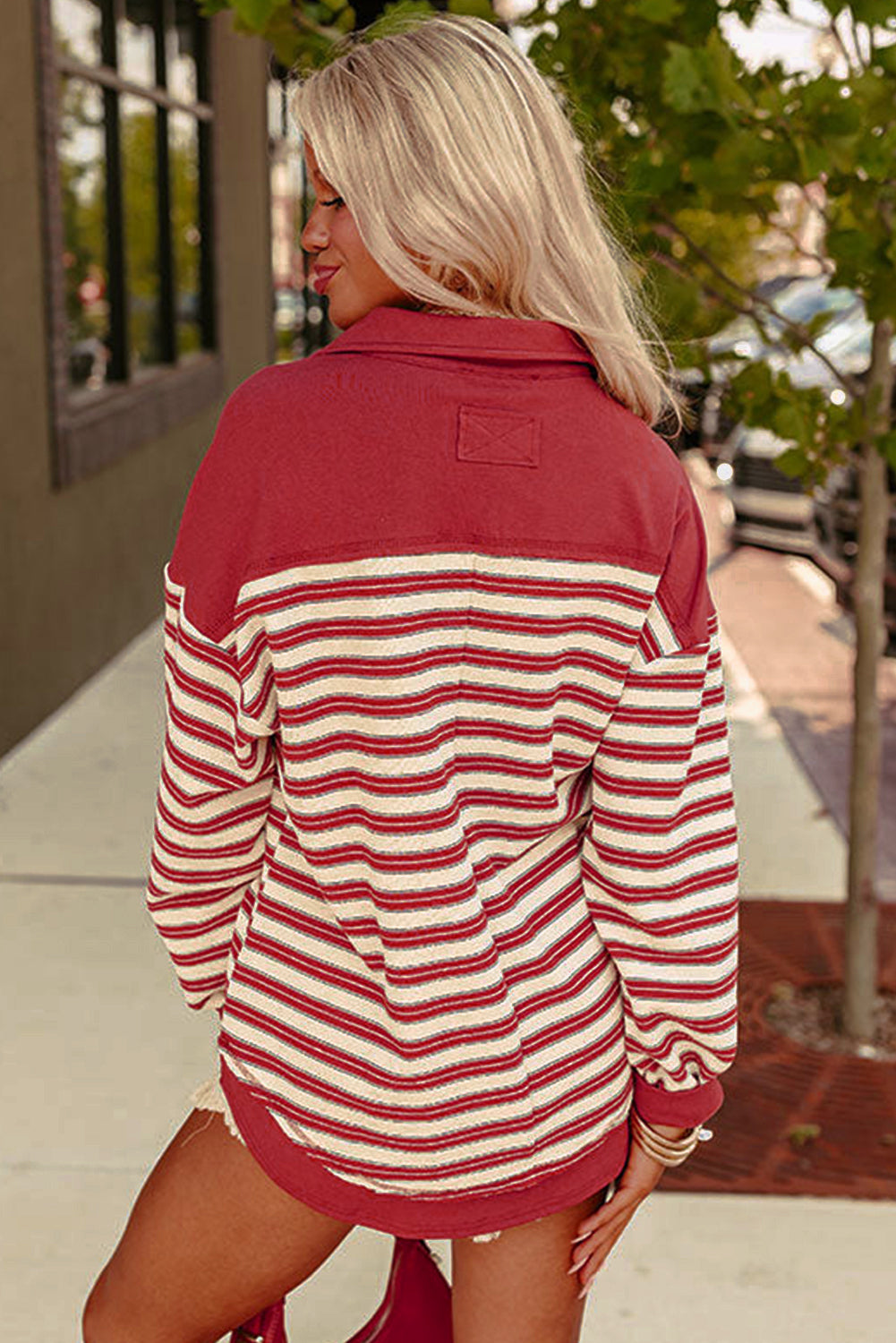 Woman wearing a red and white striped shirt with a blurred outdoor background