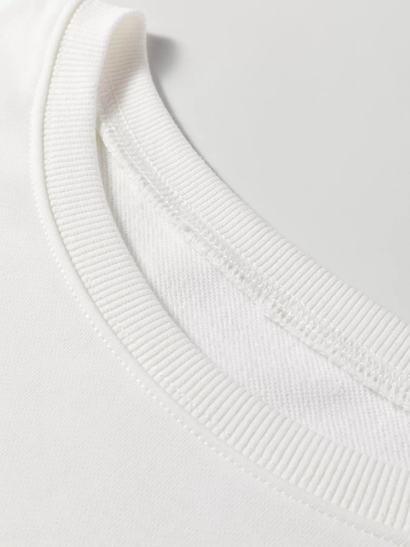 Close-up of a white sweater collar on a light gray background
