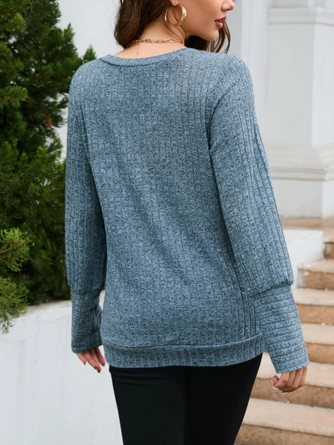 Person wearing a blue sweater standing on steps outdoors