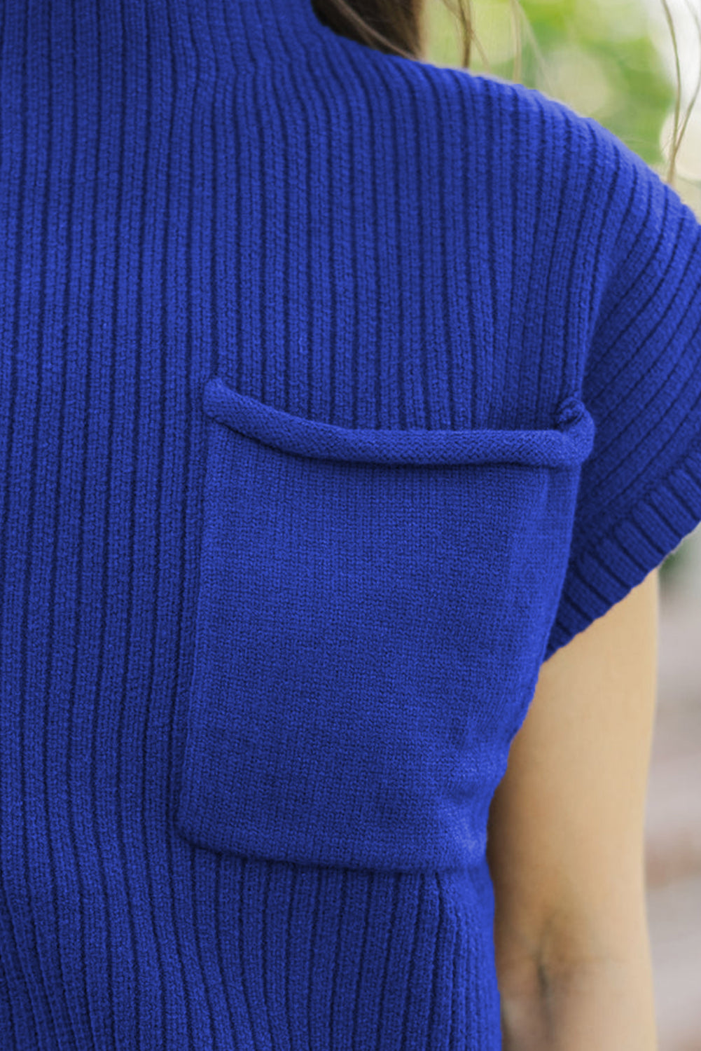 Close-up of a blue ribbed sweater with a pocket.