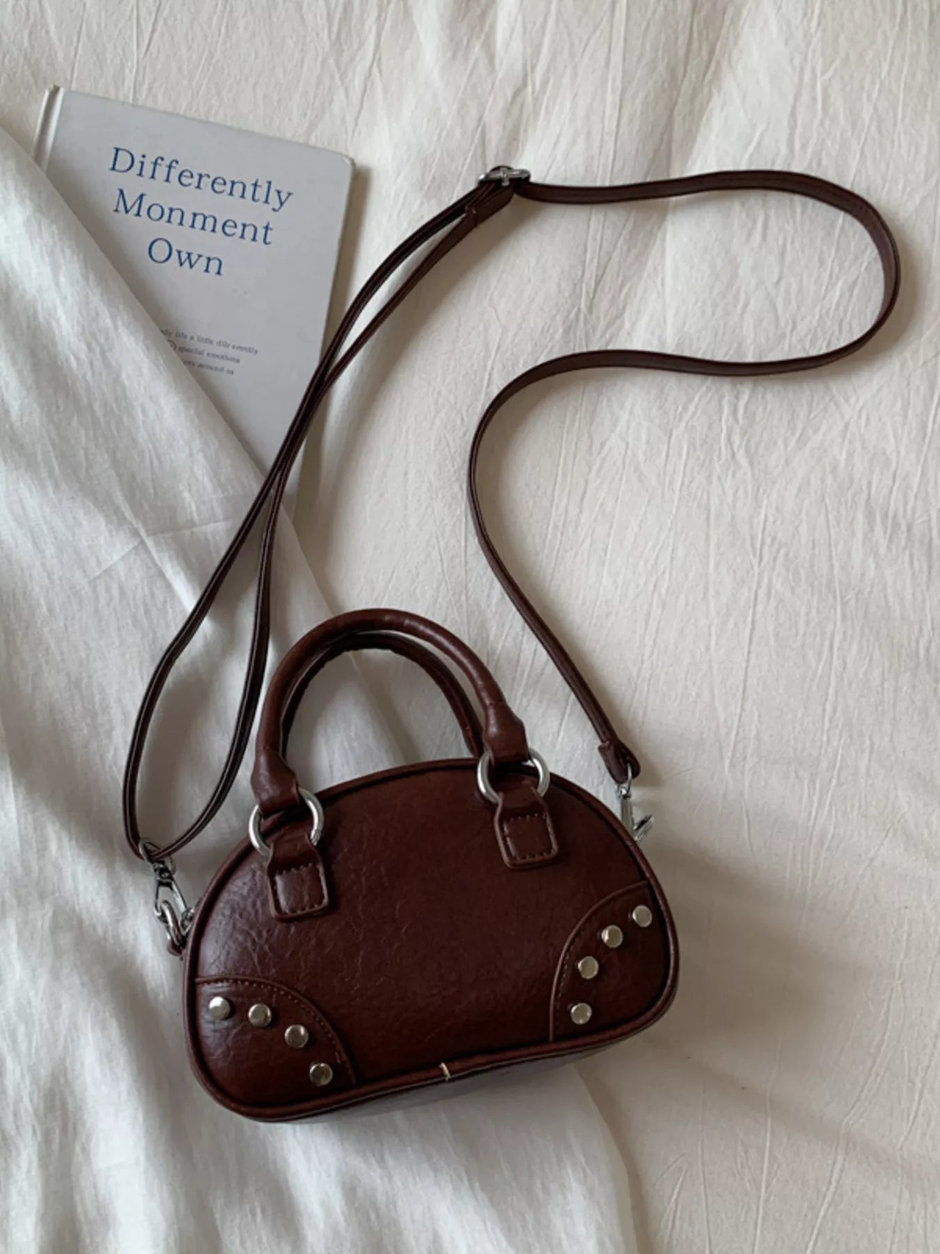 Brown handbag with a strap on a light fabric background