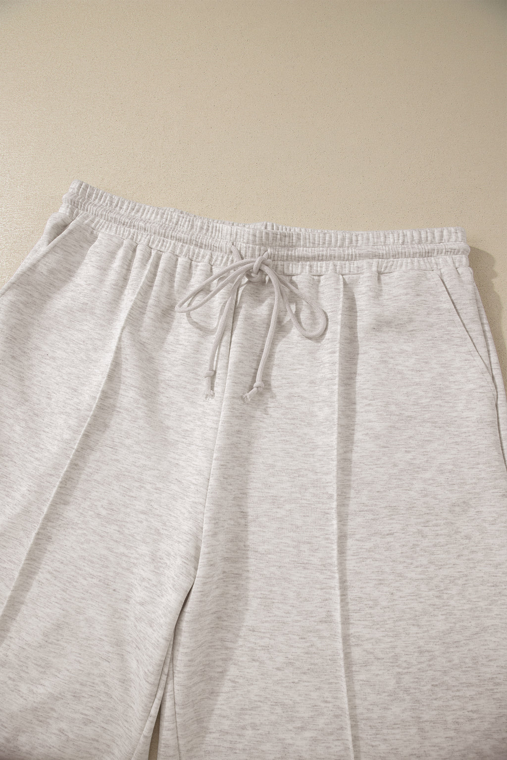 Light gray sweatpants with a drawstring on a beige background