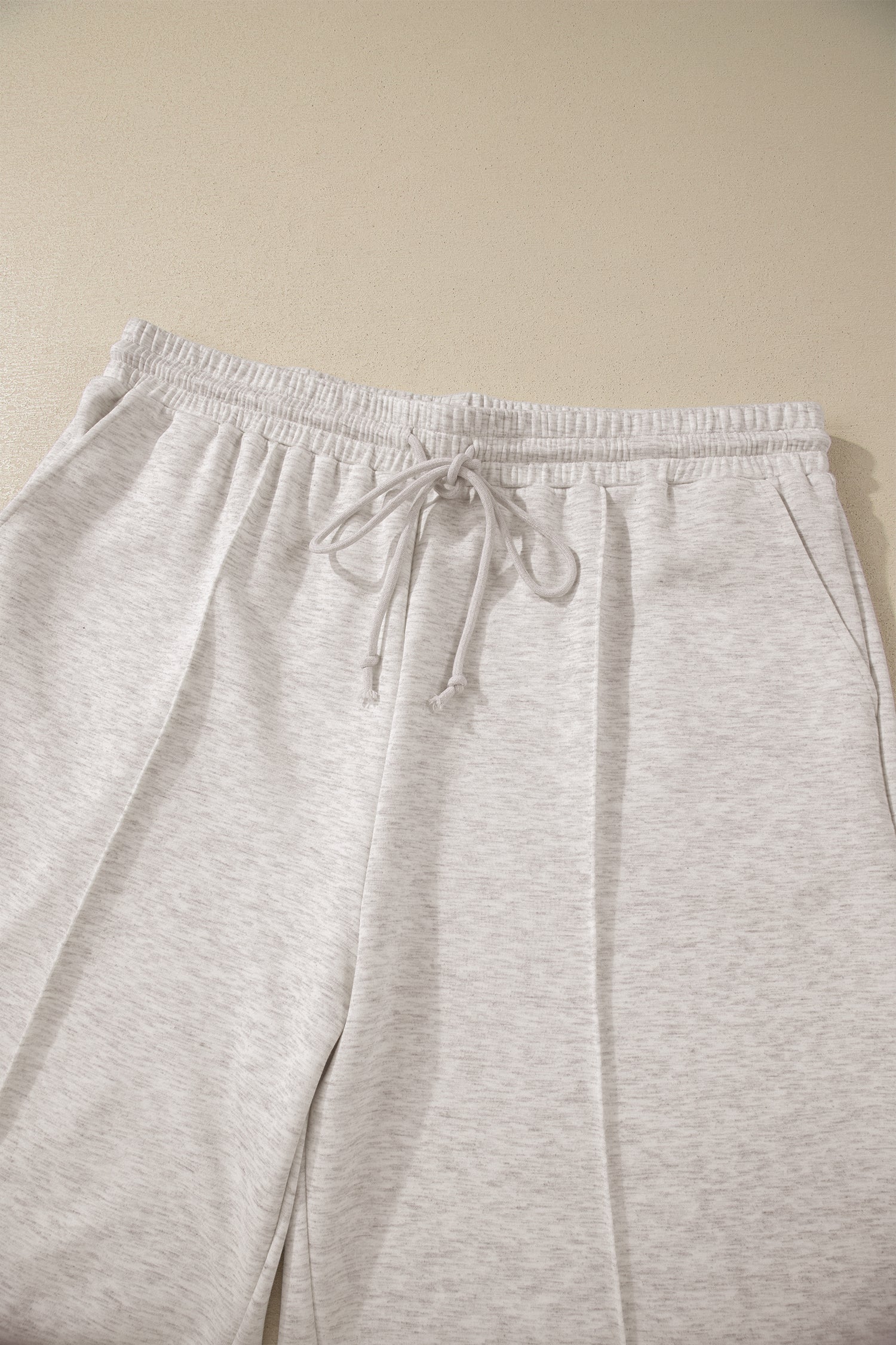 Light gray sweatpants with a drawstring on a beige background