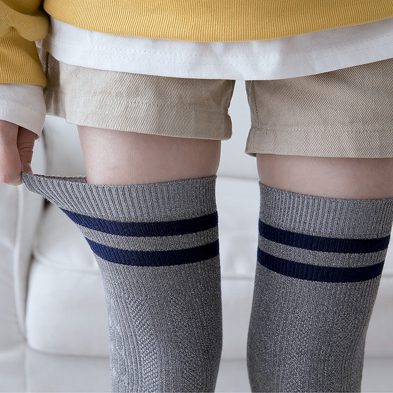 Gray knee-high socks with navy stripes worn by a person on a light background