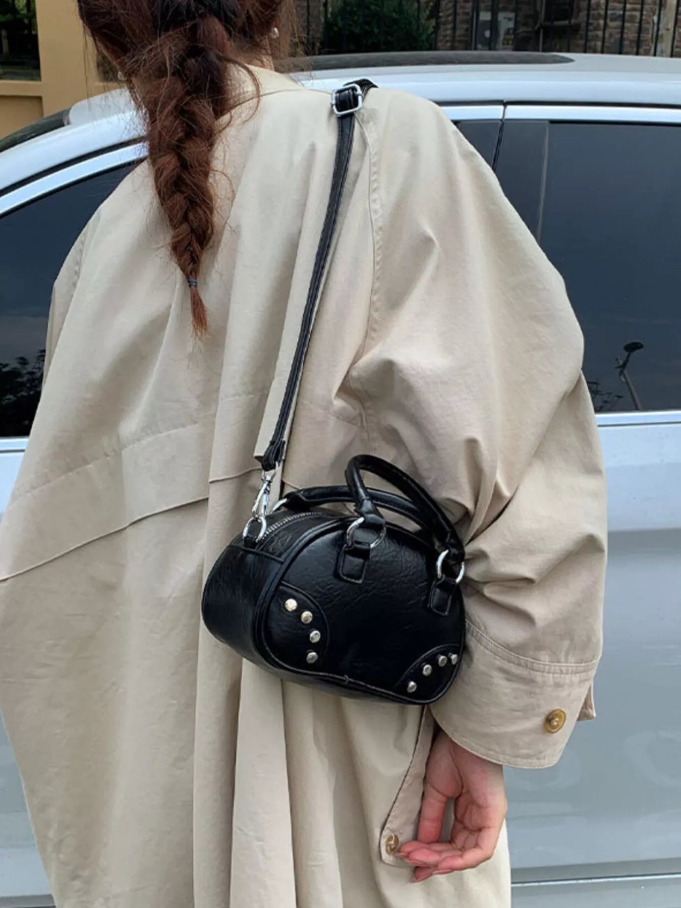 Person wearing a beige coat with a black handbag over their shoulder.