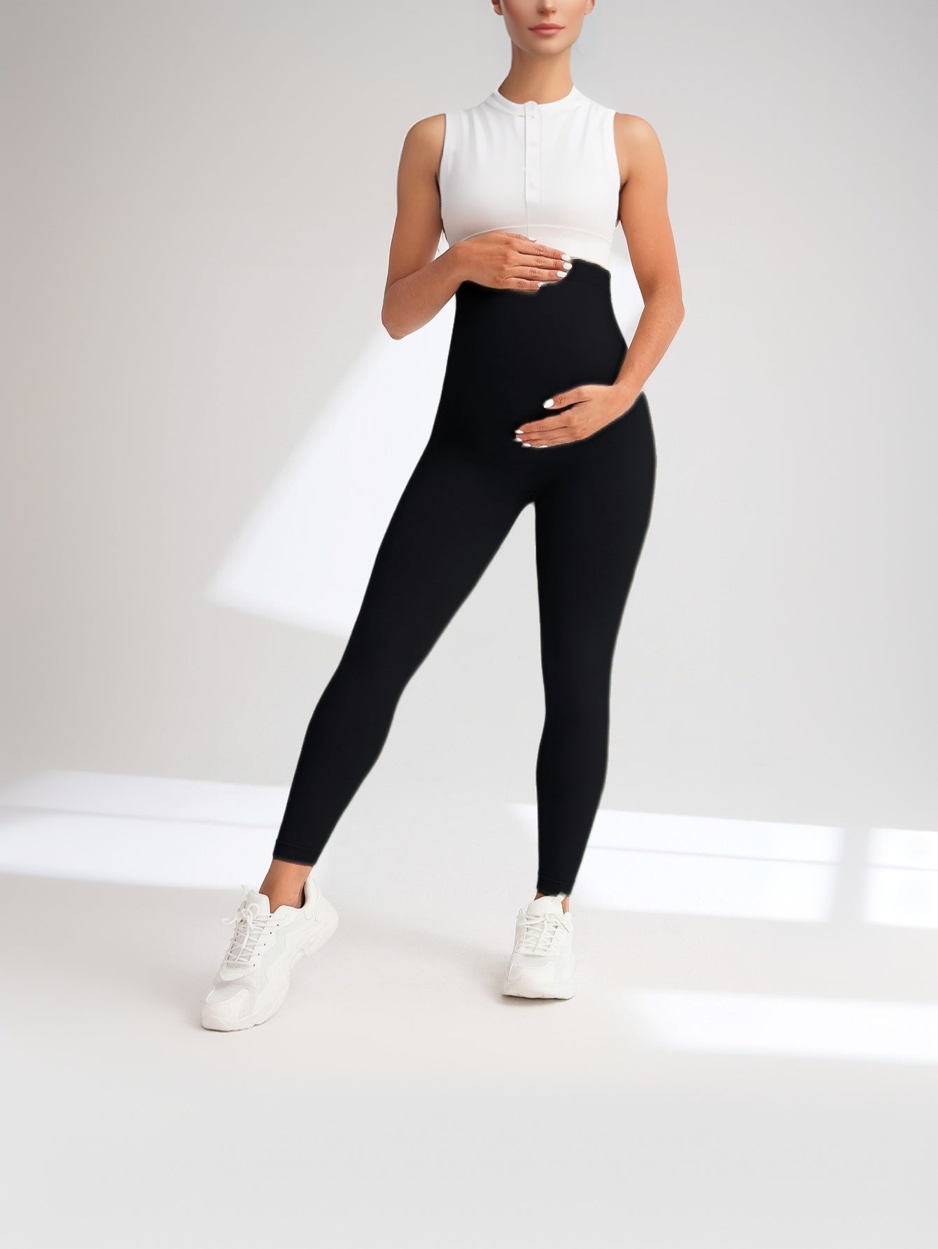 Person wearing black leggings and a white top on a light gray background