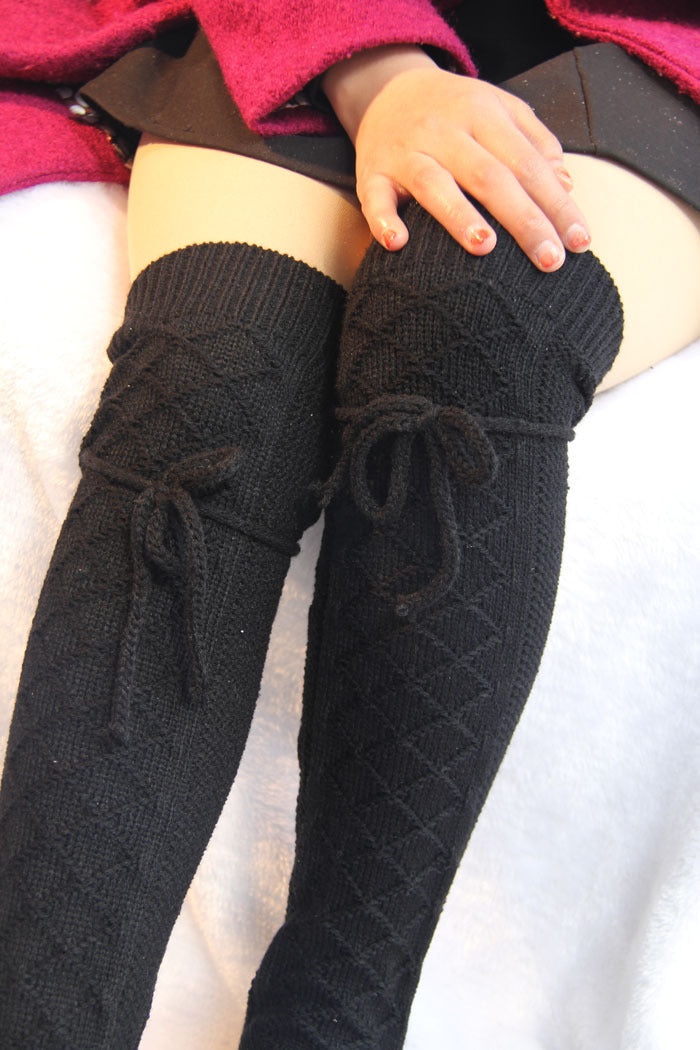 Black knitted leg warmers with bows on a white background