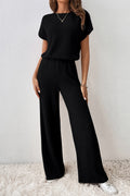 Person wearing a black ribbed knit outfit with wide-leg pants on a white background