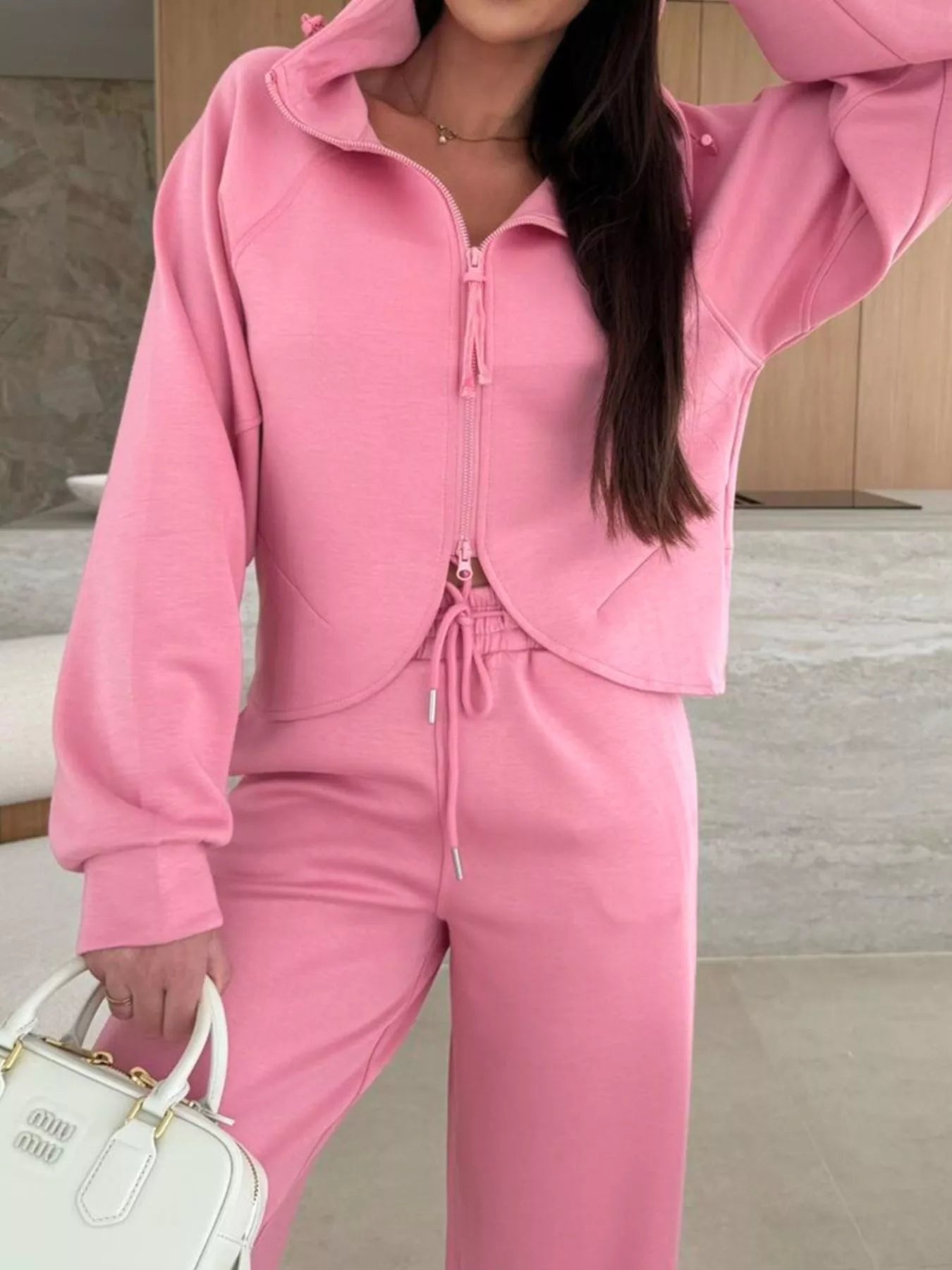 Person wearing a pink tracksuit with a neutral background