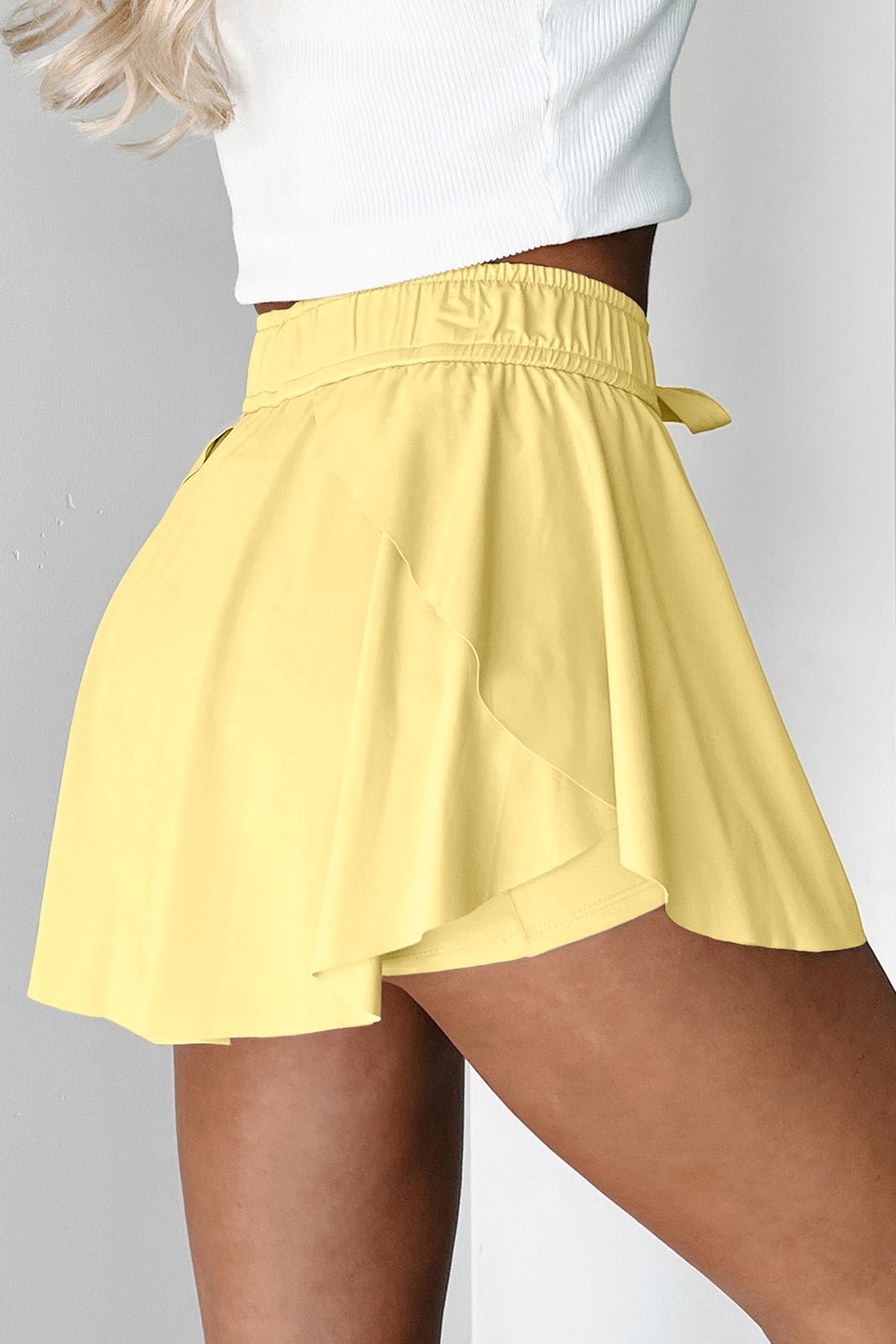Yellow tennis skort worn by a person on a plain background side view