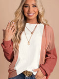 Woman wearing a white sweater with a pink cardigan against a beige background