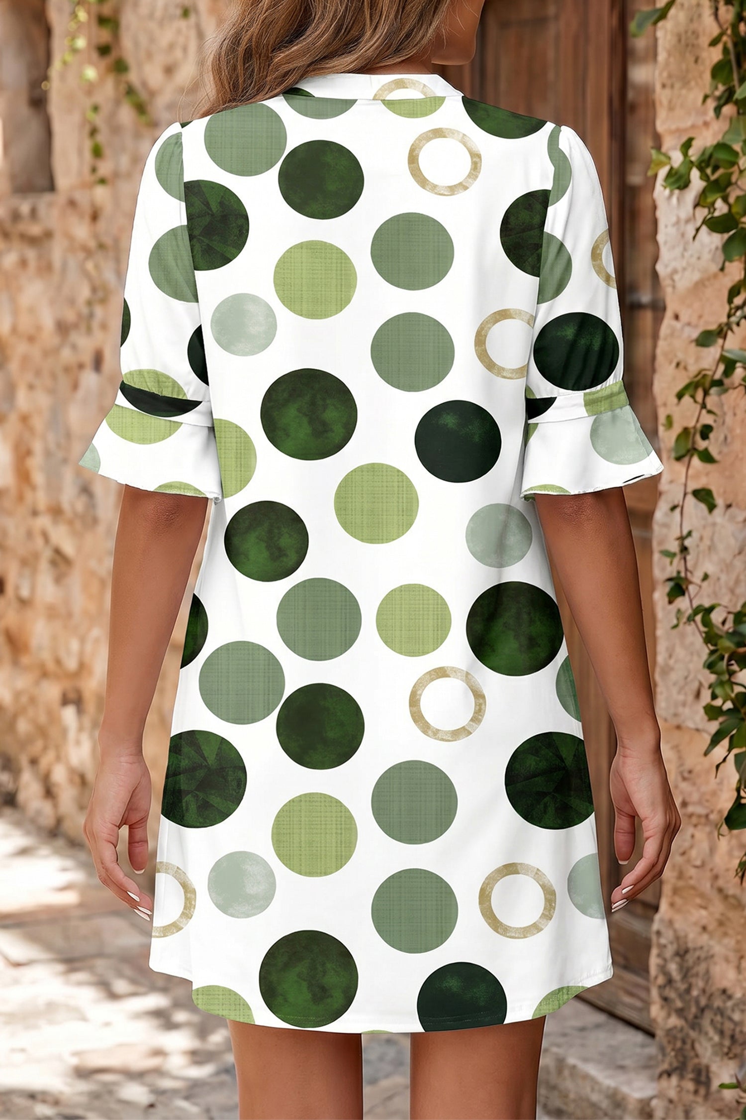 Person wearing a white dress with green and brown polka dot pattern outdoors. Back view