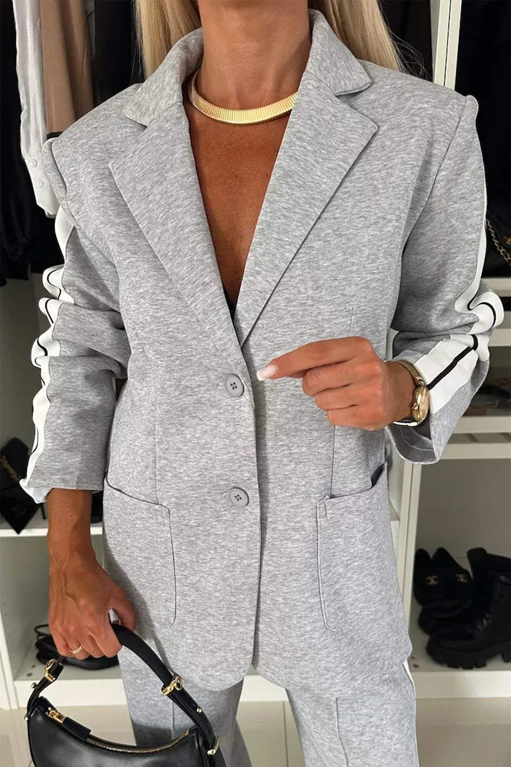 Person wearing a gray blazer with a plain background
