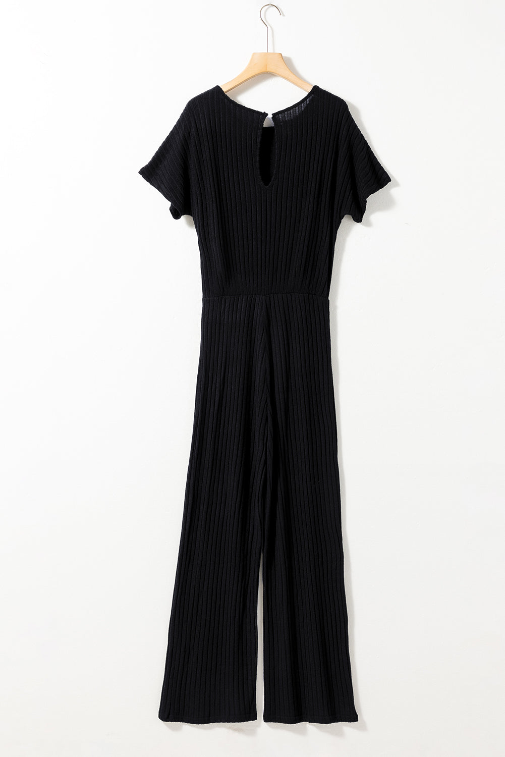 Black jumpsuit on a hanger against a white background