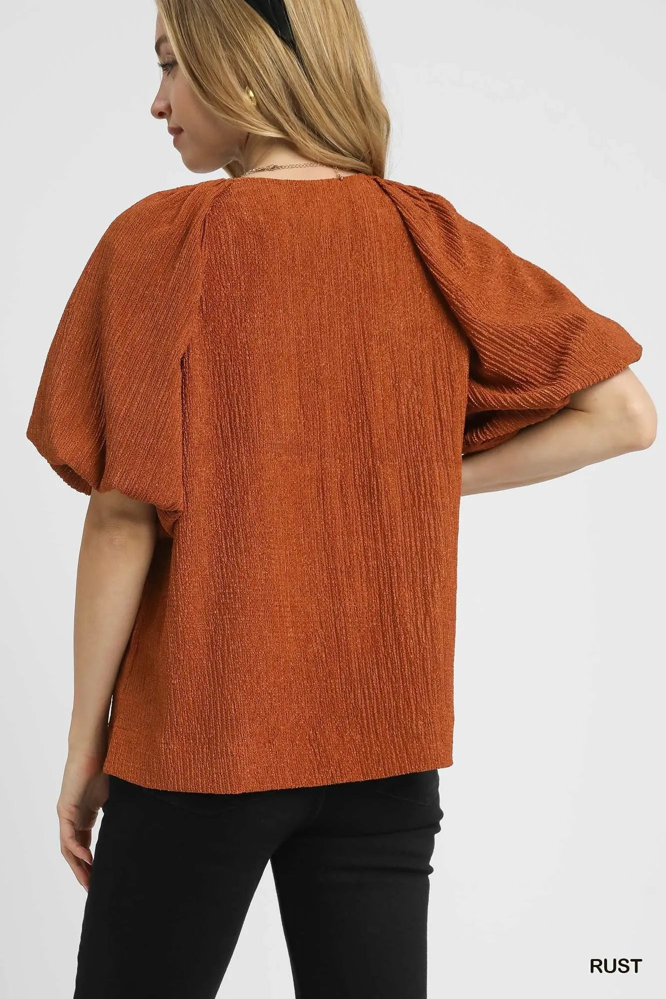 Person wearing a rust-colored textured top on a white background