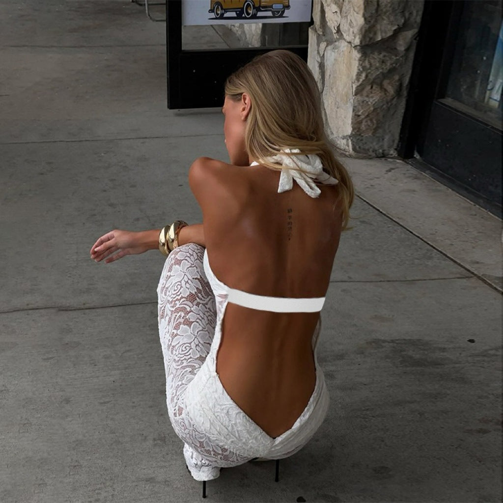 Woman in a white lace dress sitting on a concrete floor.