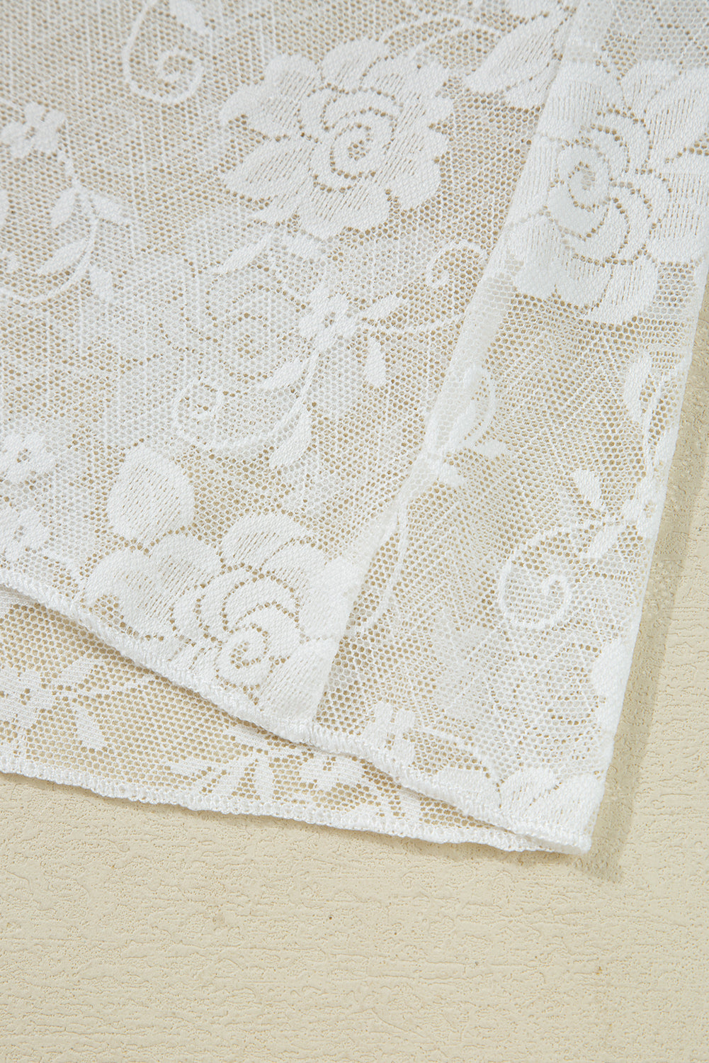 Close-up of white lace fabric on a beige background