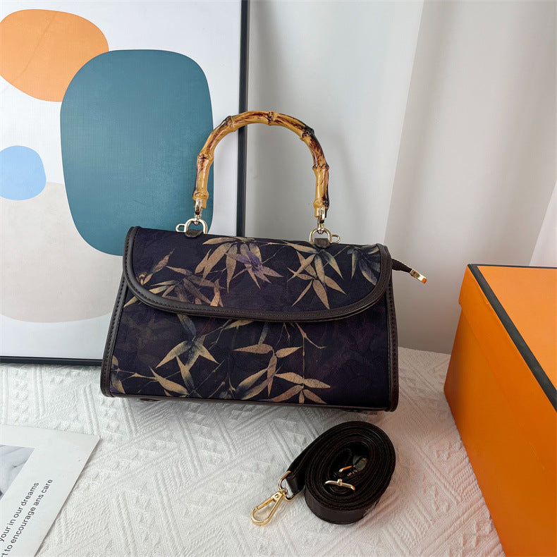 Handbag with bamboo pattern and wooden handle on a textured surface