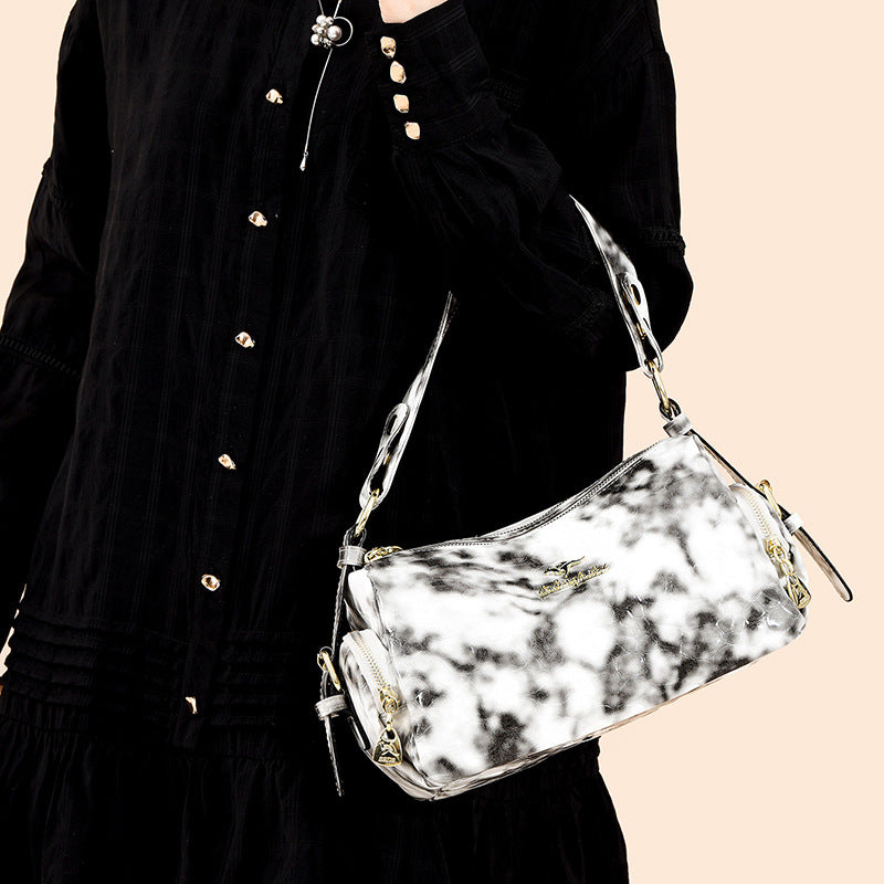 Person holding a marble-patterned handbag with a black outfit